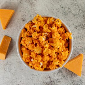 Cheddar cheese popcorn in bowl with cheese pieces